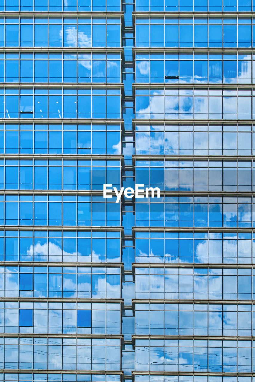 FULL FRAME SHOT OF GLASS BUILDING WITH BLUE WALL