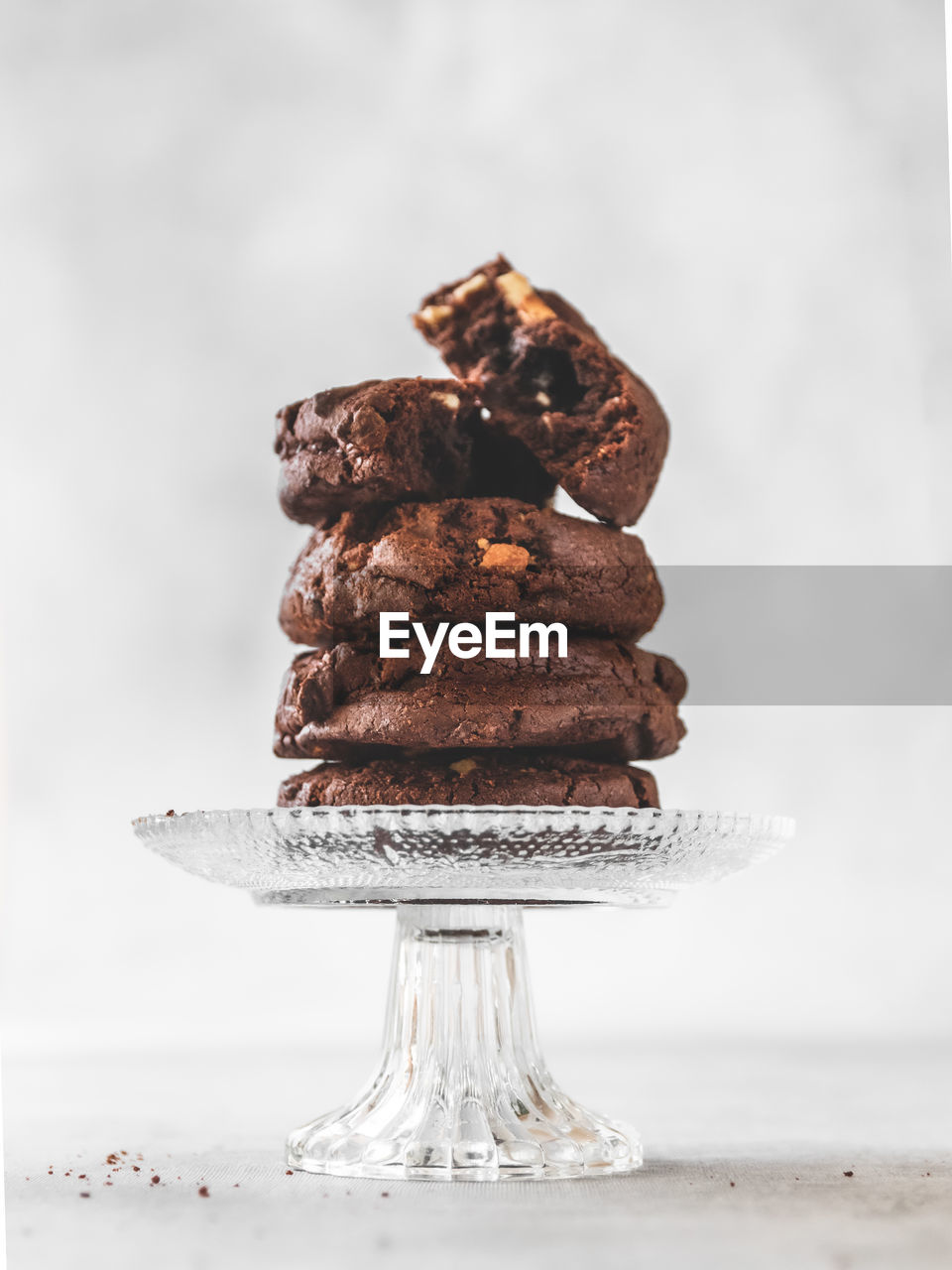 Close-up of stack of chocolate chip cookies on crystal glass stand on table 