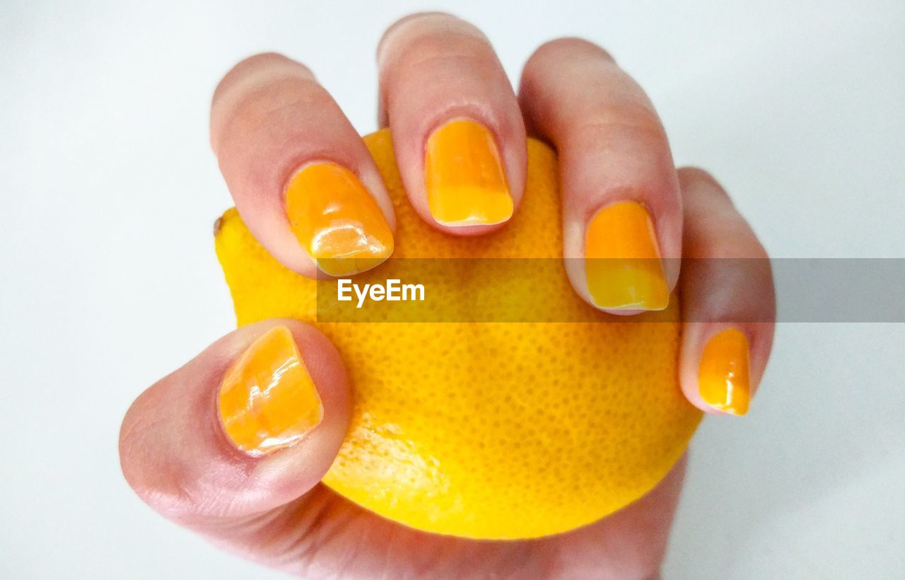 CLOSE-UP OF PERSON HAND HOLDING ORANGE