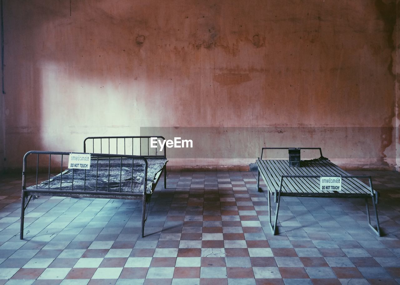 Empty beds on tiled floor at tuol sleng genocide museum