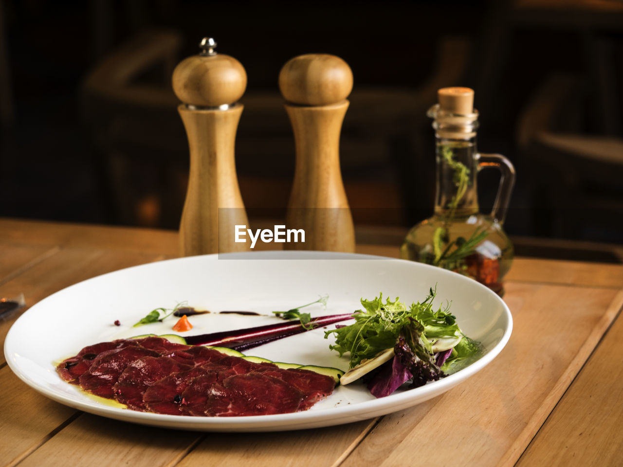 Close-up of food in plate with pepper mills on table