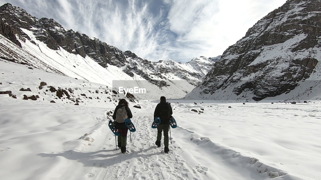 REAR VIEW OF PEOPLE WALKING ON SNOWCAPPED MOUNTAIN