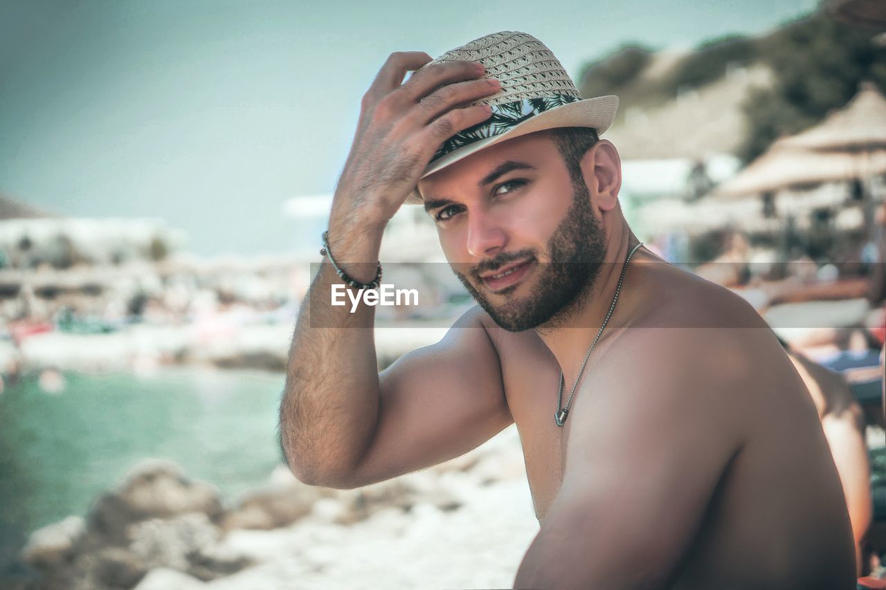 Portrait of handsome man wearing hat at beach