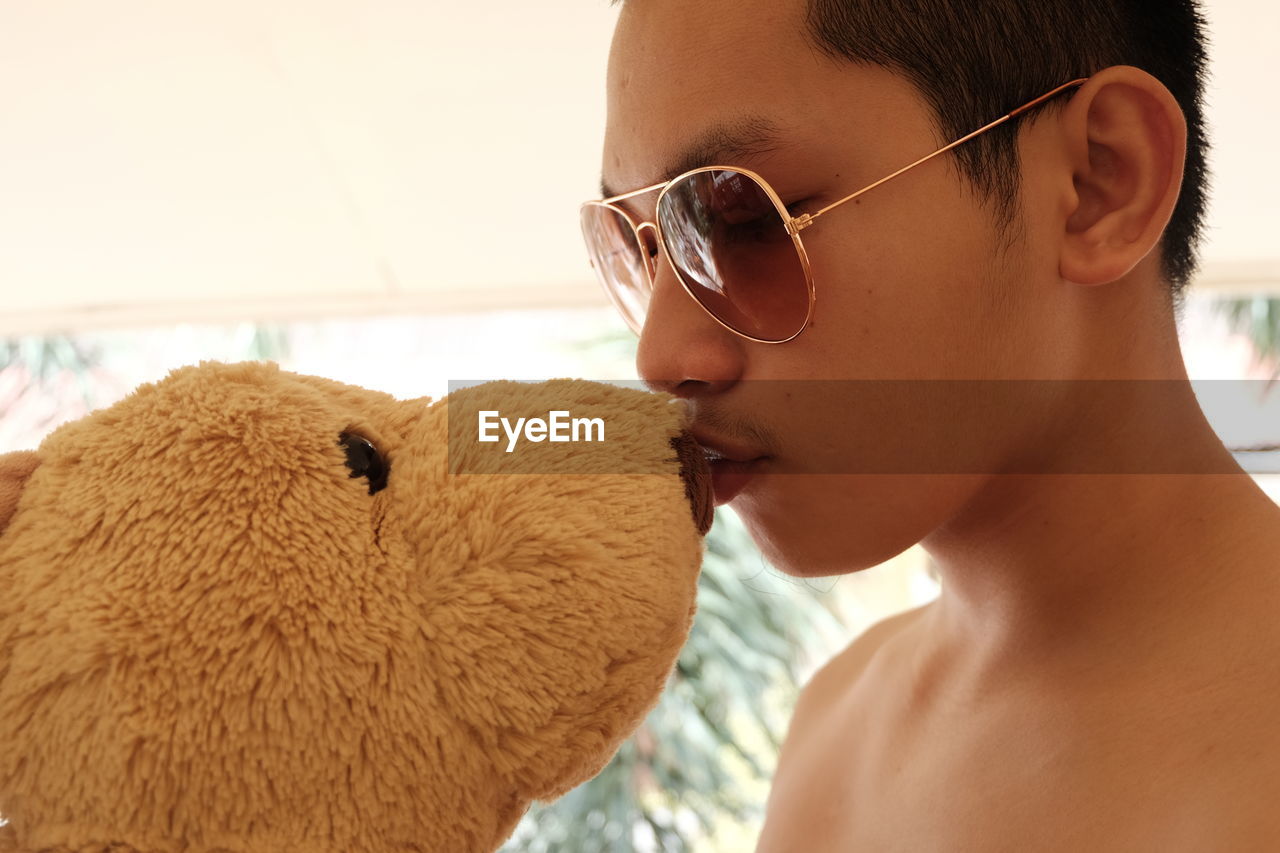 Close-up of shirtless boy kissing stuffed toy