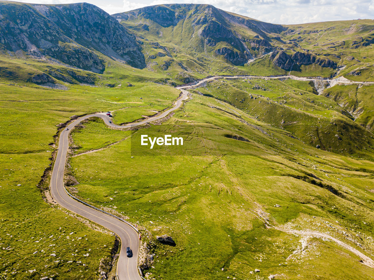 Winding road from high mountain pass, in summer time. aerial view by drone . romania