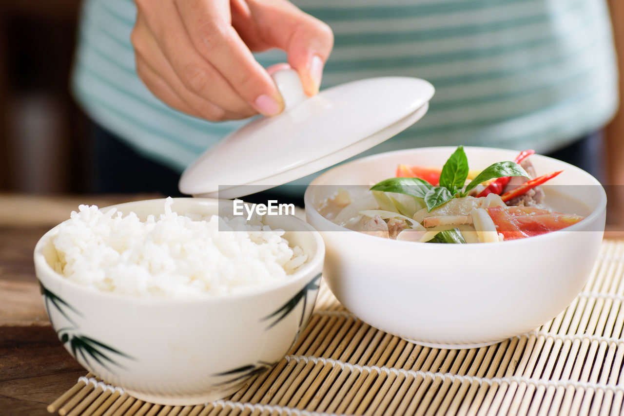 Midsection of woman with food in bowls on table