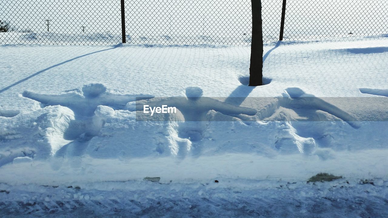 Human prints on snow covered land against fence