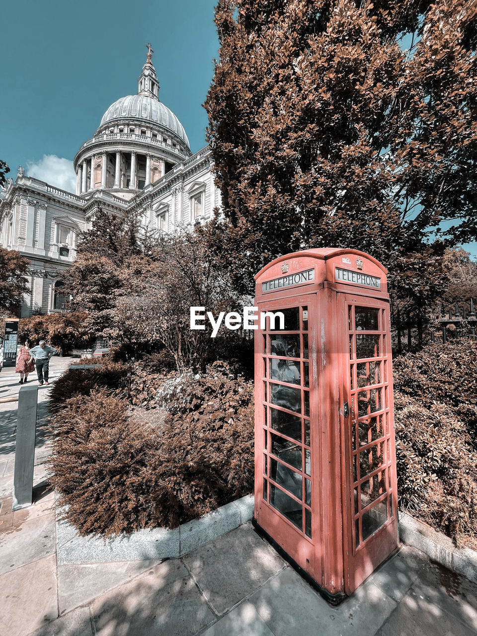 TELEPHONE BOOTH BY BUILDING AGAINST TREES