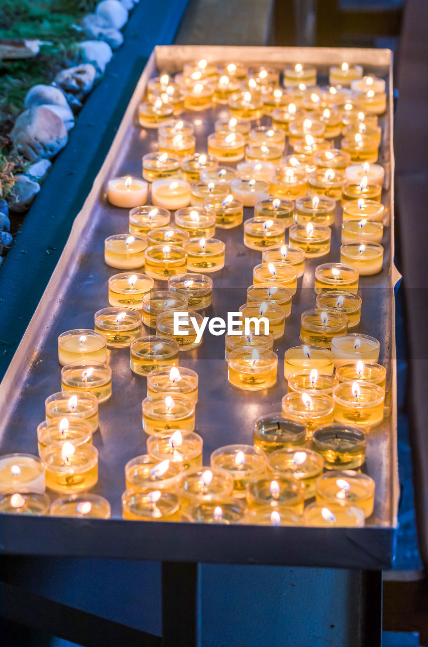 High angle view of lit tea light candles on table