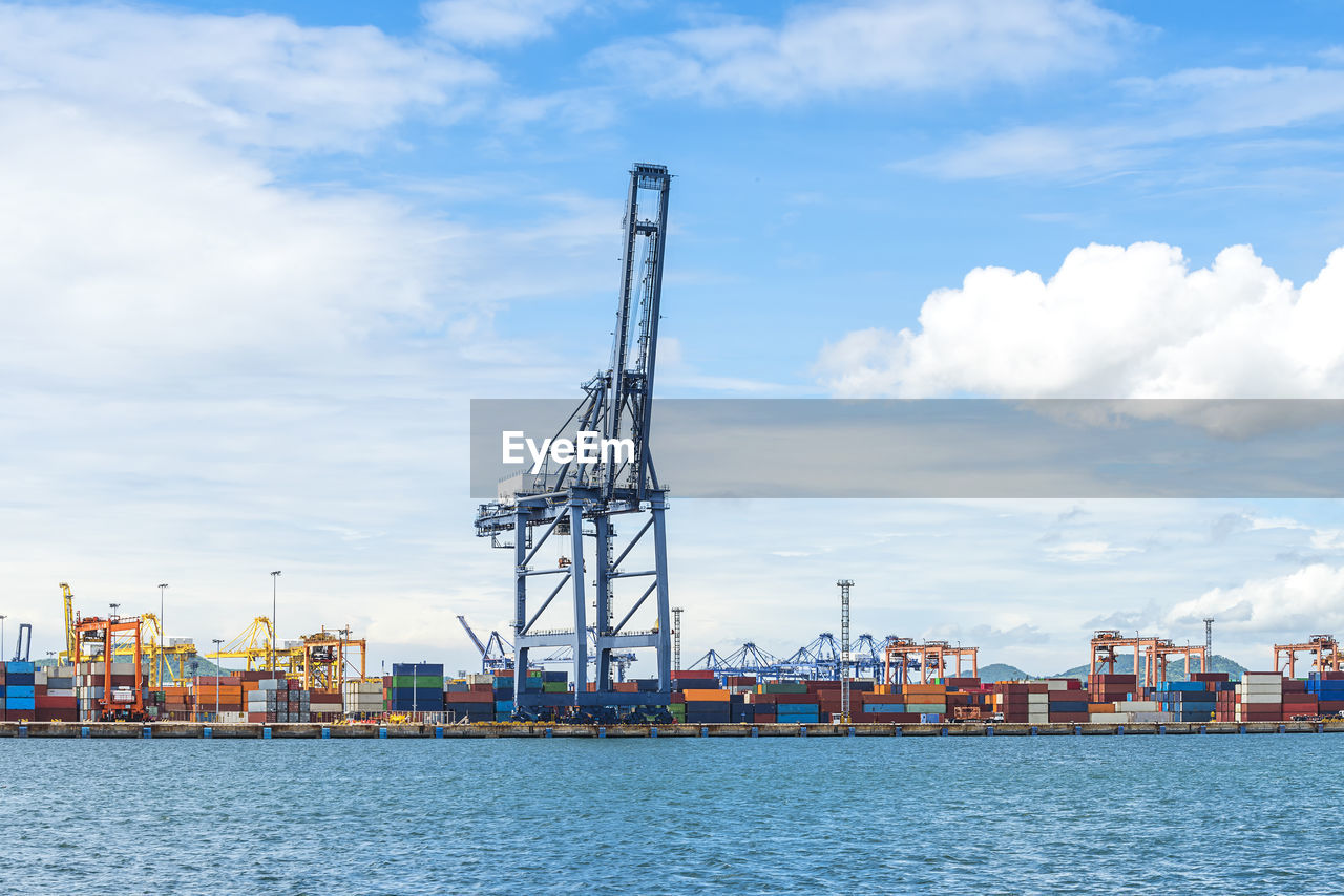 CRANES AT PIER AGAINST SKY