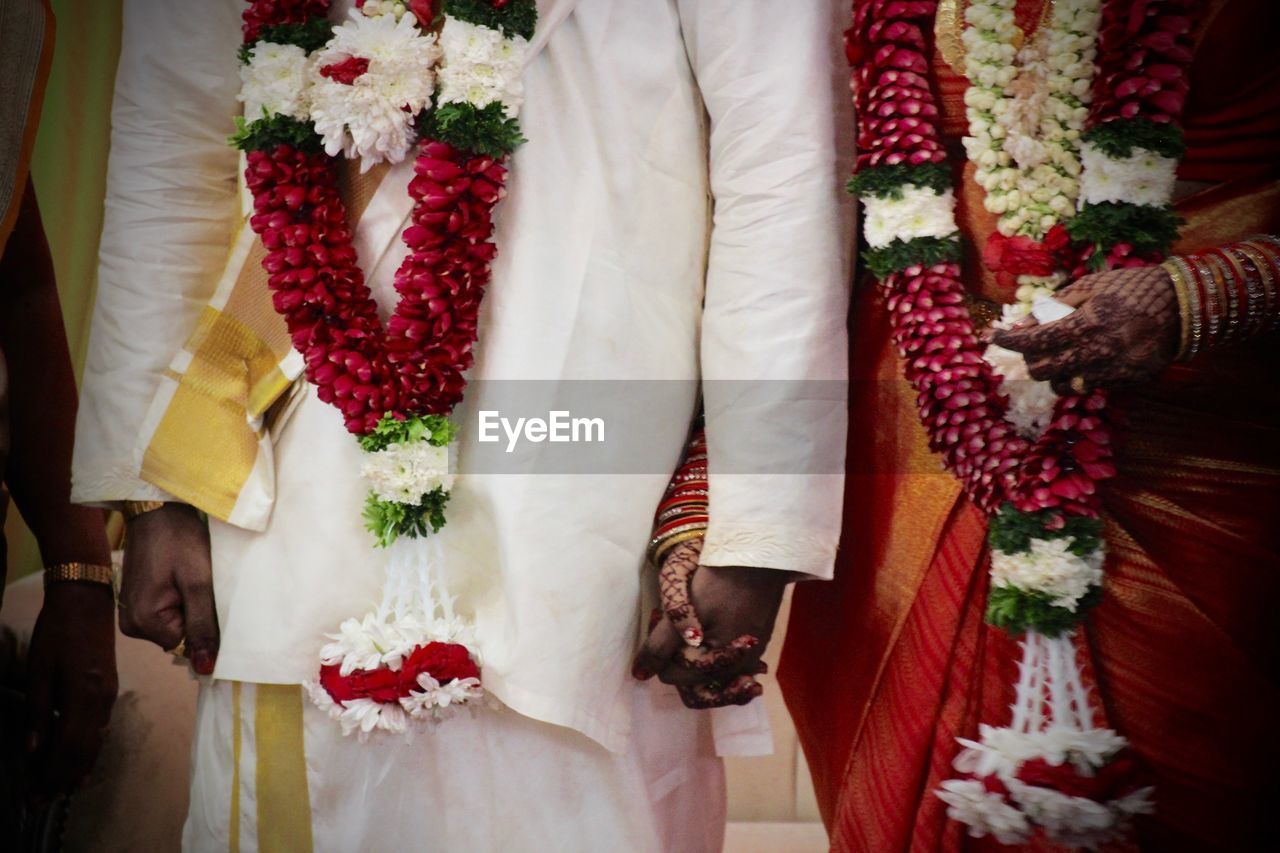 Midsection of bride and bridegroom holding hands during wedding ceremony