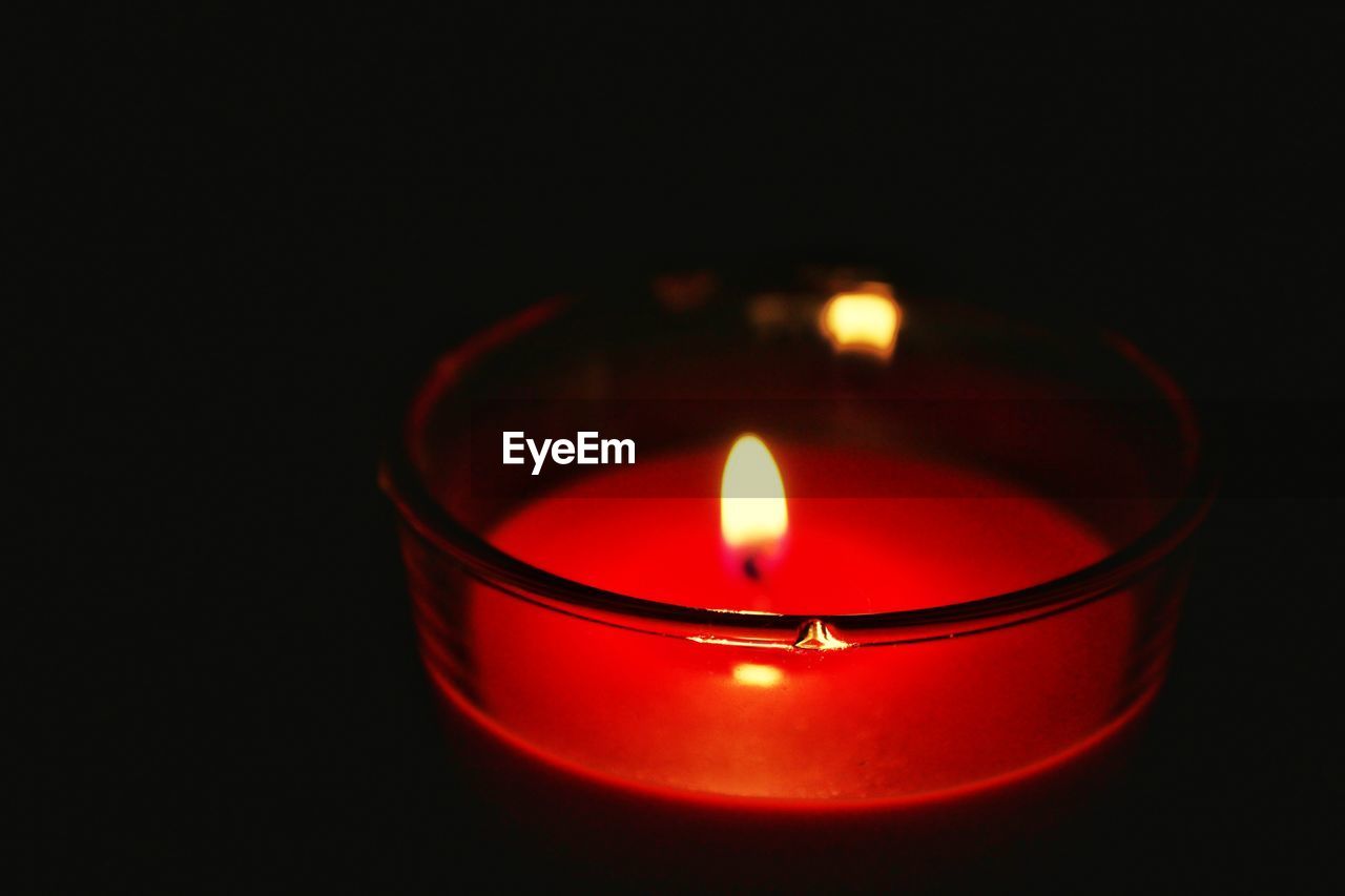 Close-up of lit candle against black background