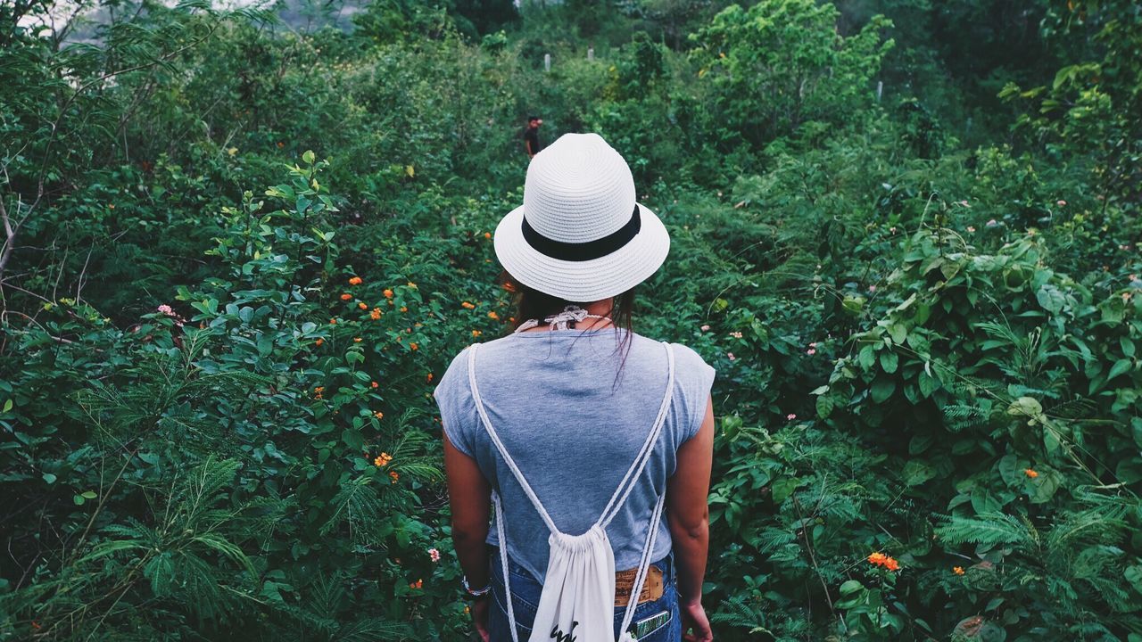 REAR VIEW OF A WOMAN STANDING IN GRASS