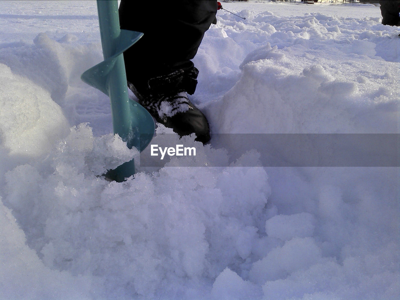 LOW SECTION OF PERSON STANDING ON SNOW FIELD