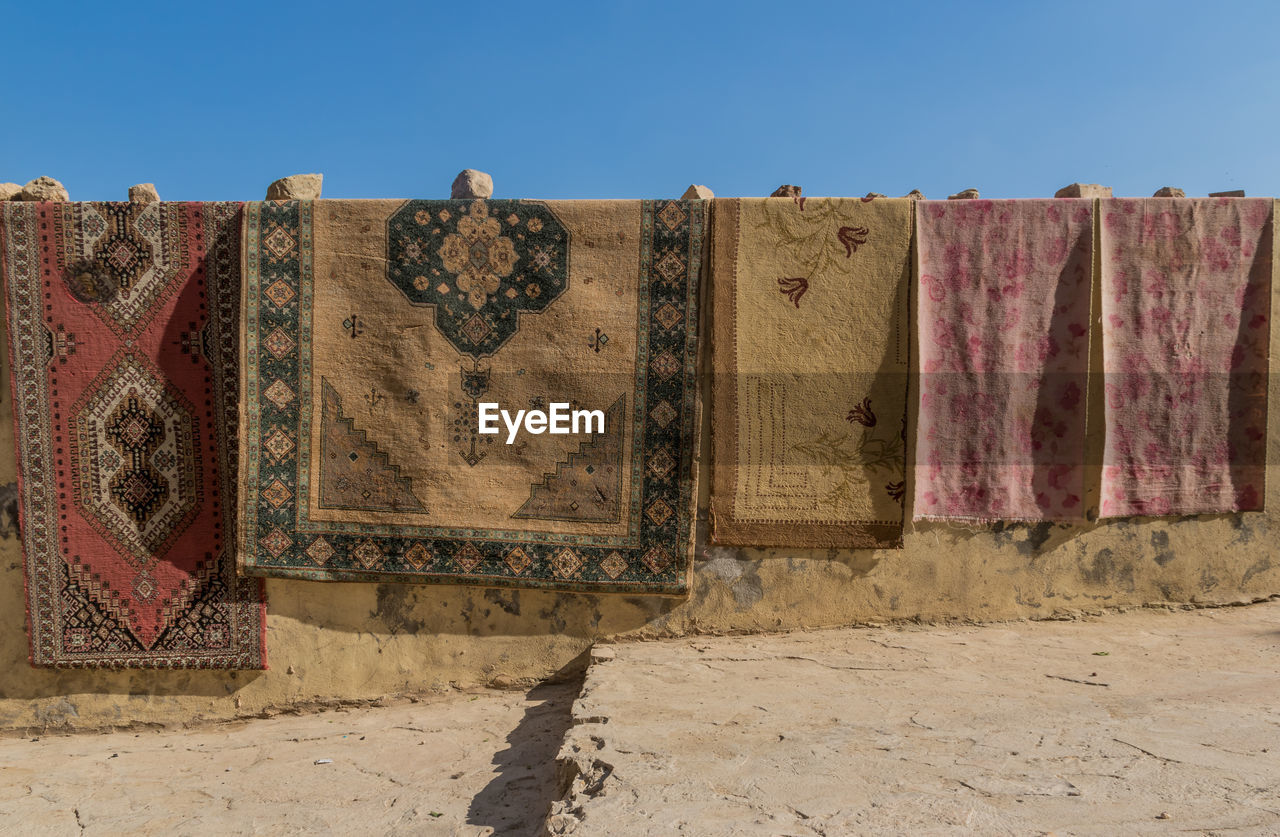 LOW ANGLE VIEW OF CLOTHES DRYING AGAINST WALL