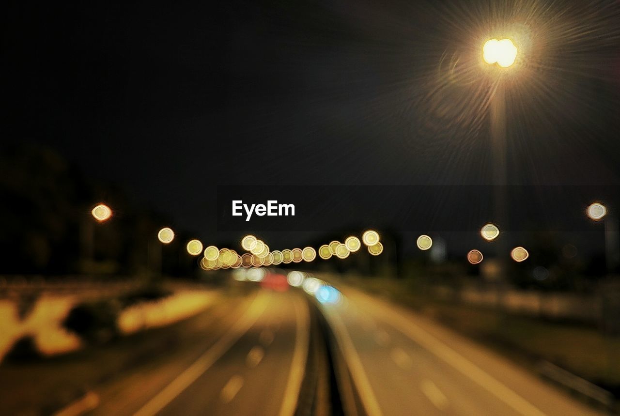 Defocused image of illuminated street lights in city at night