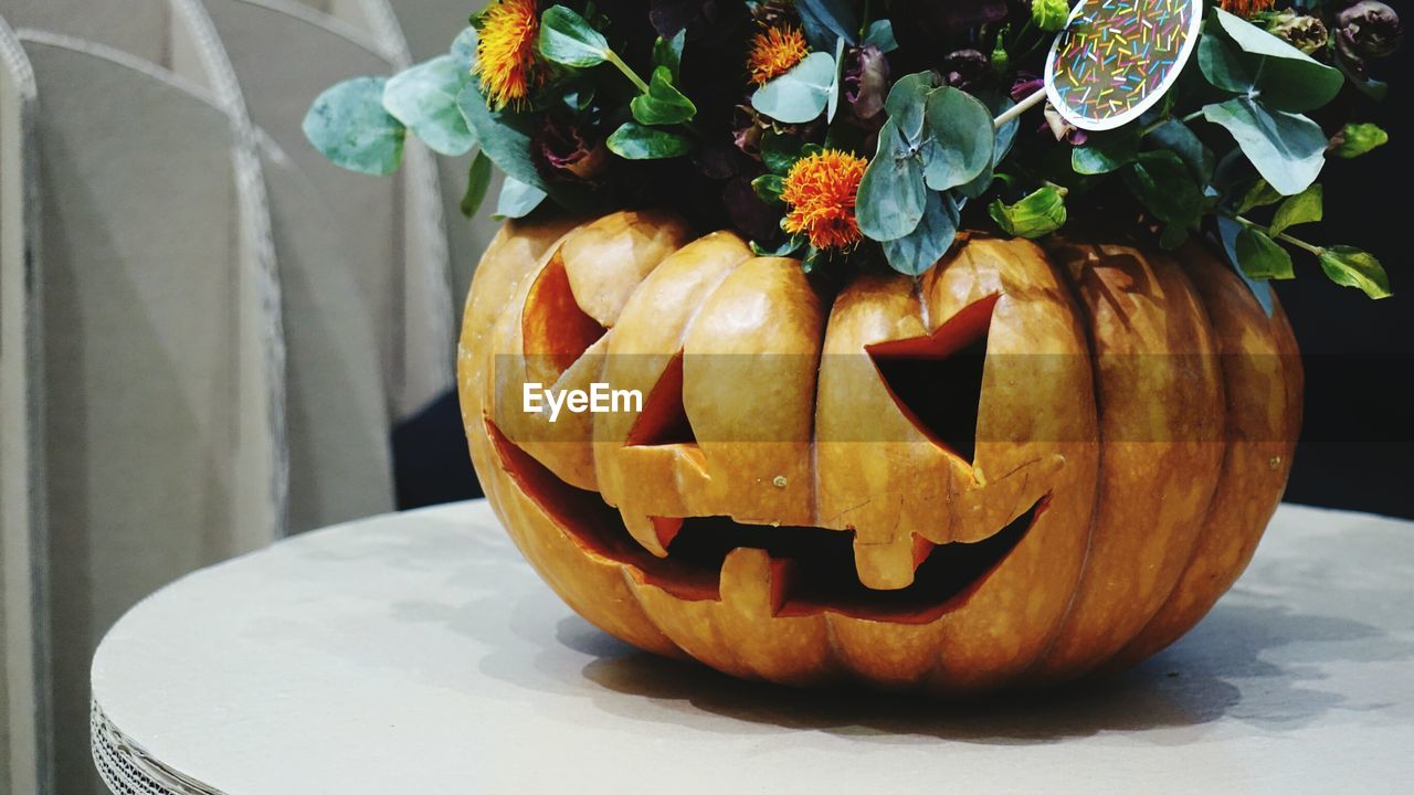 Close-up of pumpkin with flowers on table. halloween