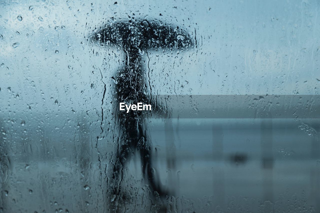 Person seen through of wet glass window in rainy season