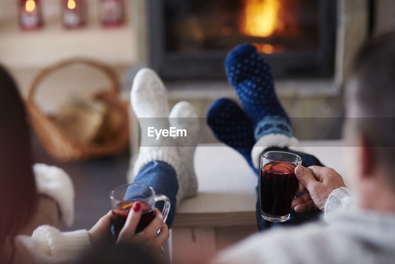 Mature couple with hot drinks in living room at the fireplace