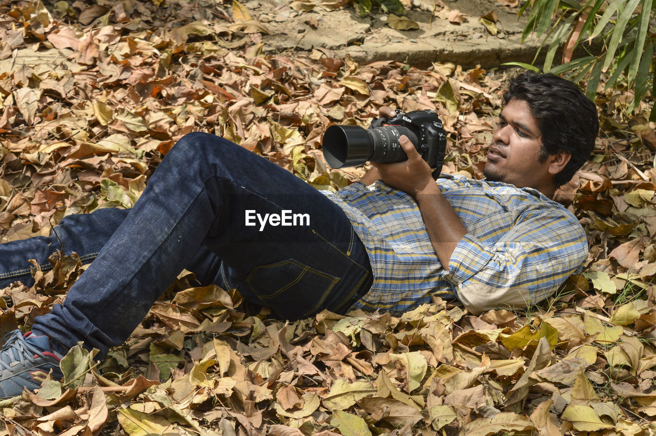 SIDE VIEW OF YOUNG MAN LYING ON GROUND