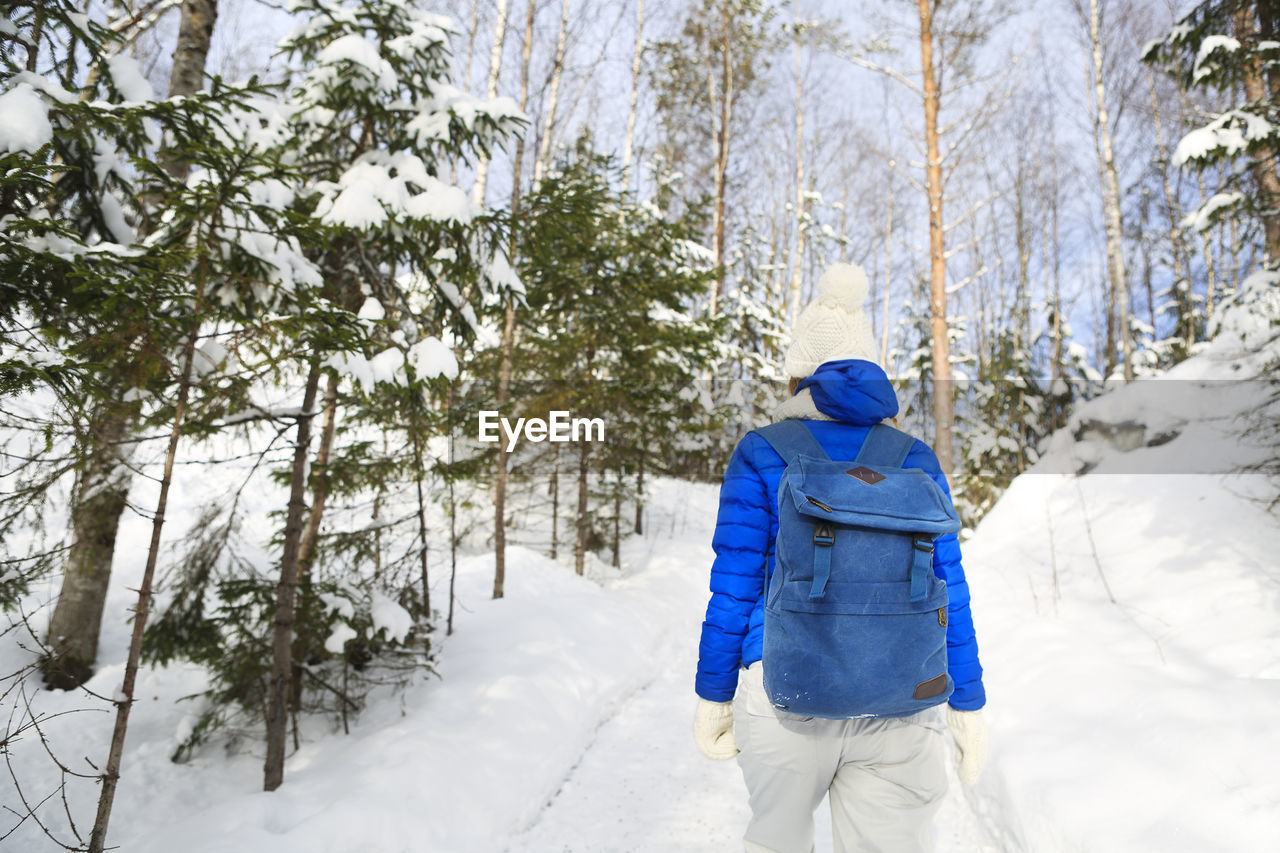 Rear view of man hiking on snow covered forest