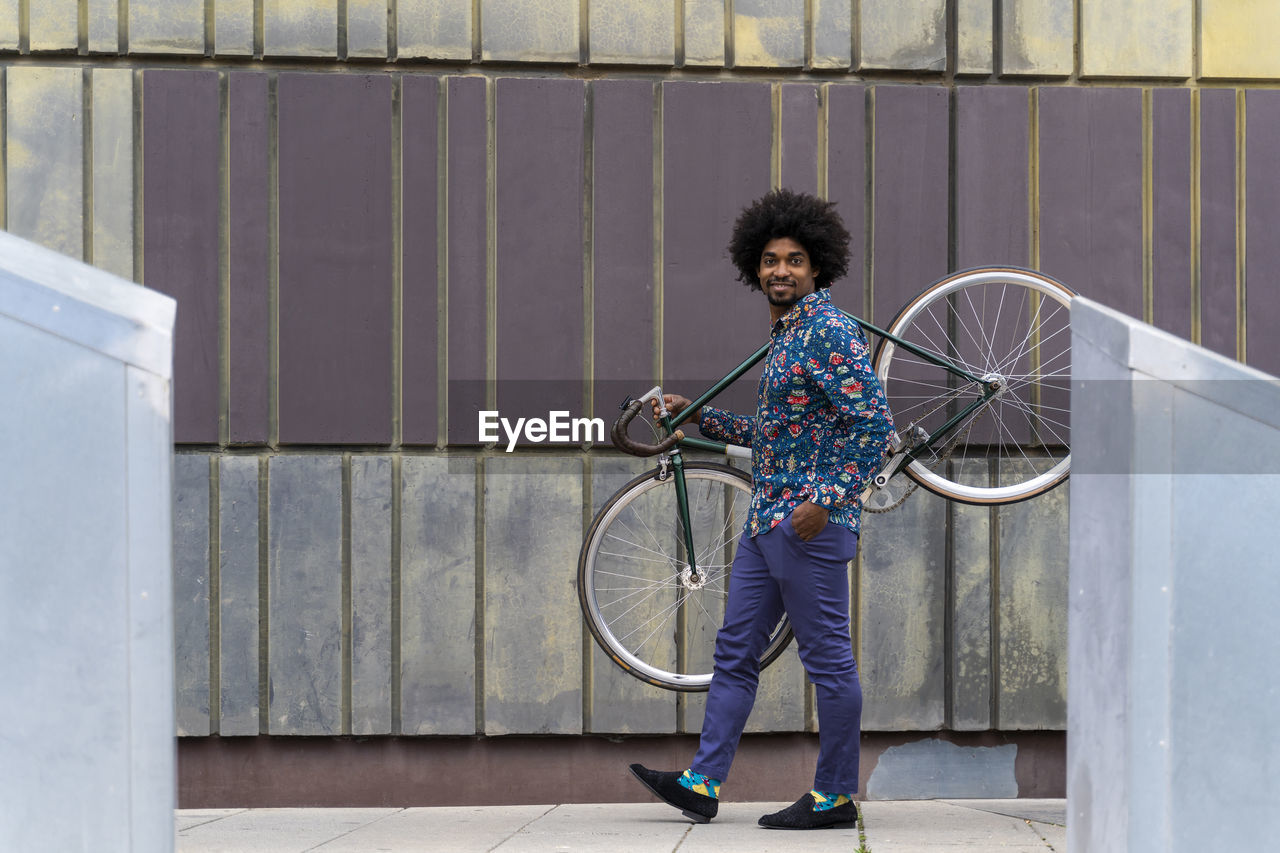 Stylish man carrying bicycle in the city