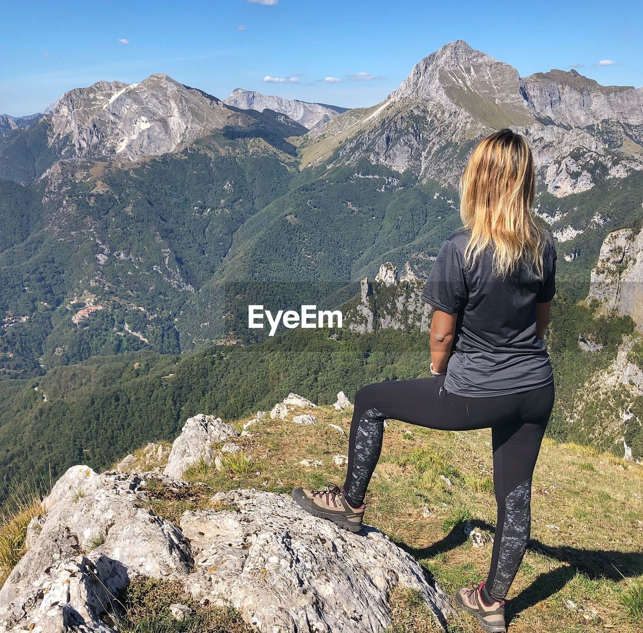 Rear view of mid adult woman standing mountain against blue sky