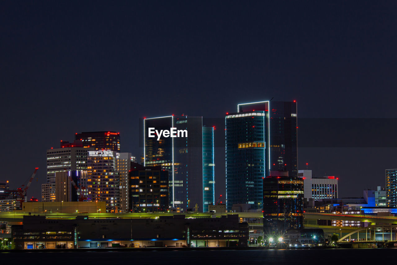 Illuminated modern buildings against clear sky at night