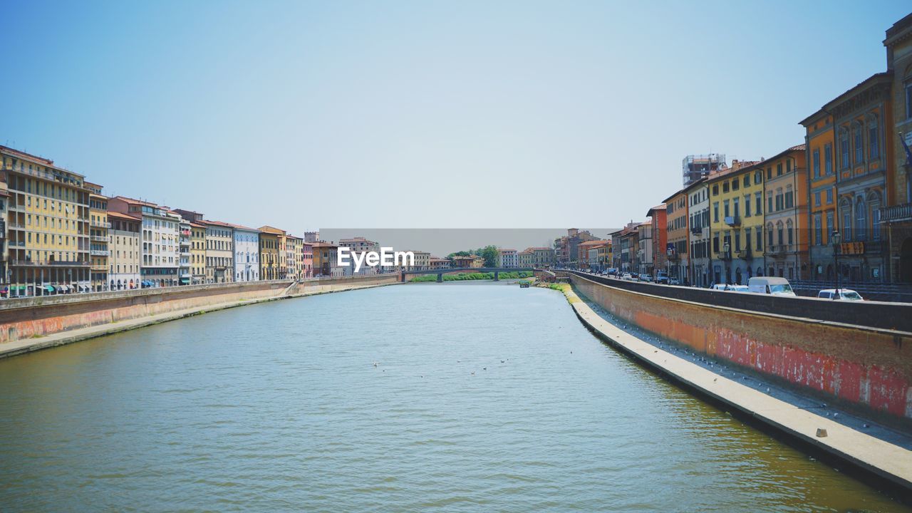 Canal in city against clear sky