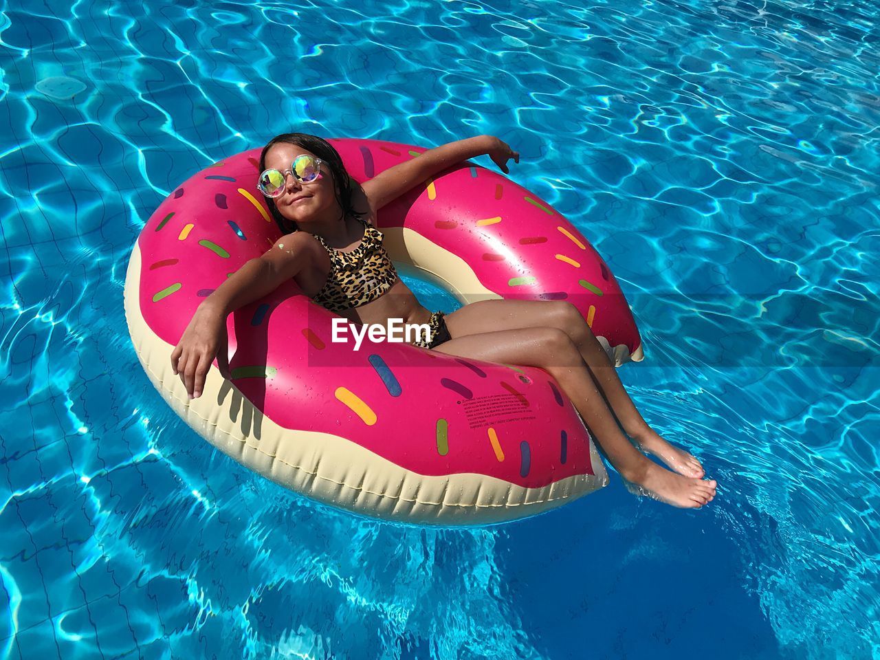 High angle view of smiling girl on inflatable ring floating at swimming pool