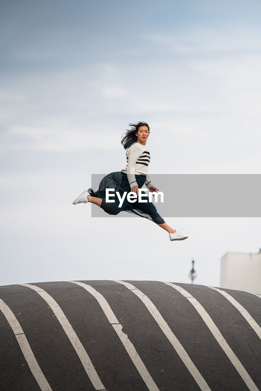 Woman jumping in mid-air against sky