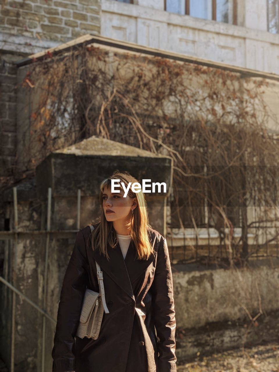 Young woman wearing hat standing against bare tree