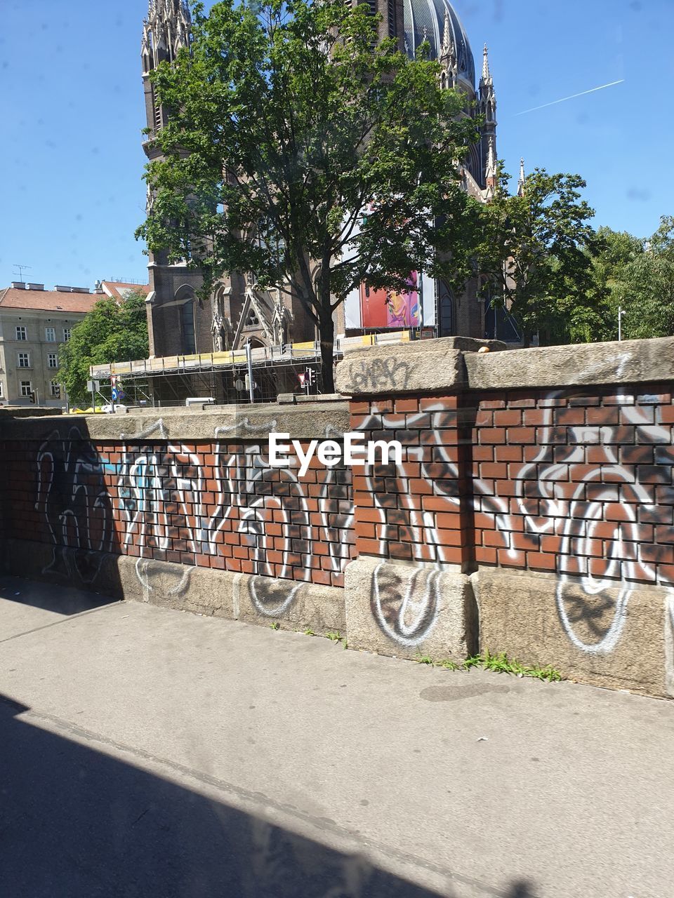 GRAFFITI ON WALL BY ROAD IN CITY AGAINST SKY