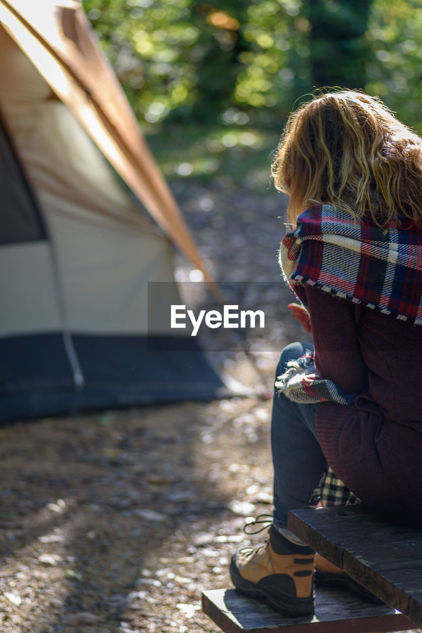 Rear view of woman sitting on picnic table