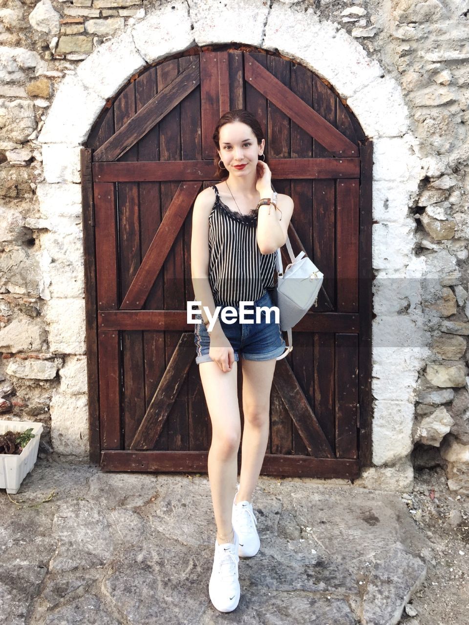 Portrait of smiling beautiful woman standing against closed door