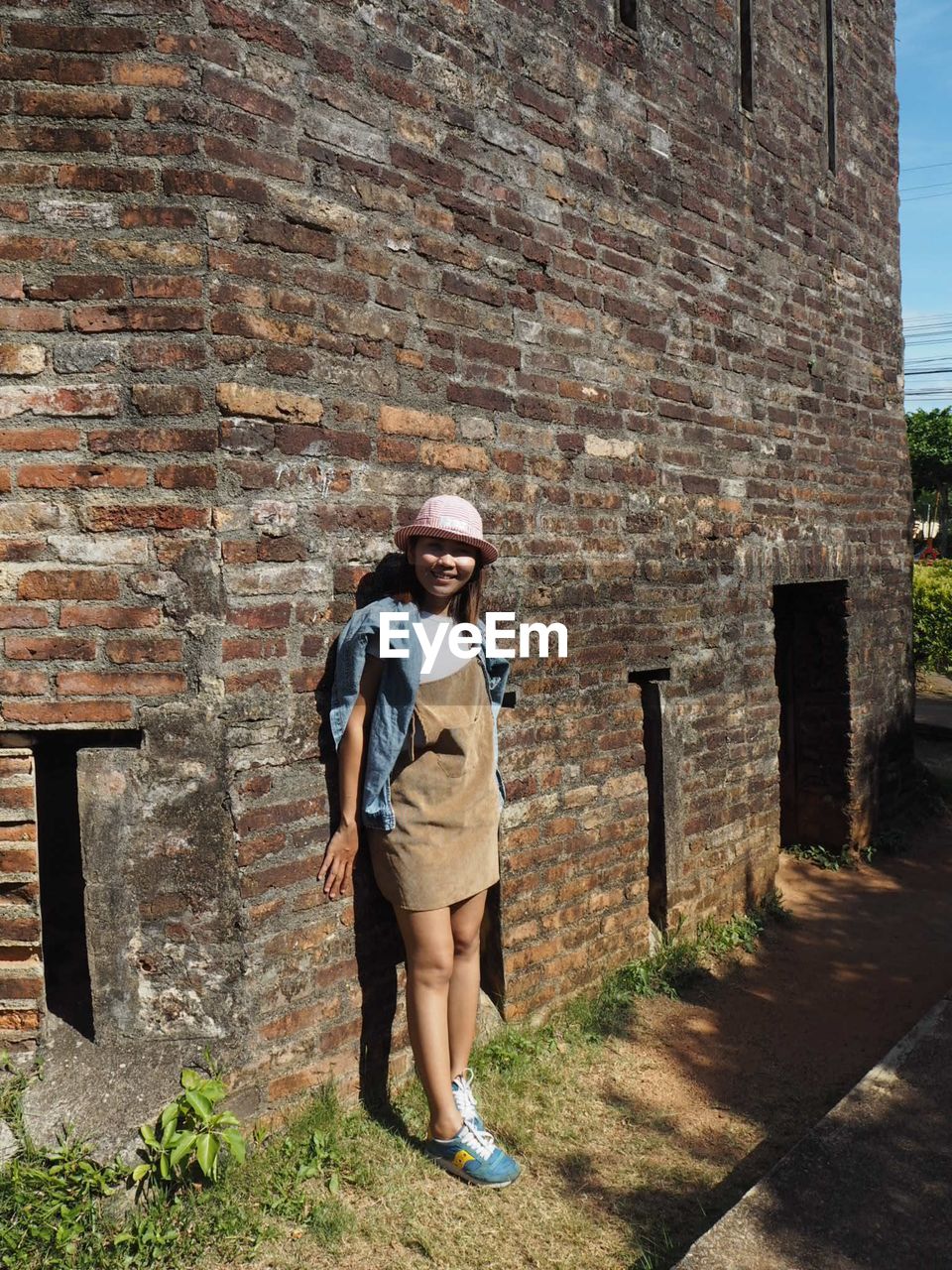 Full length of young woman standing against building