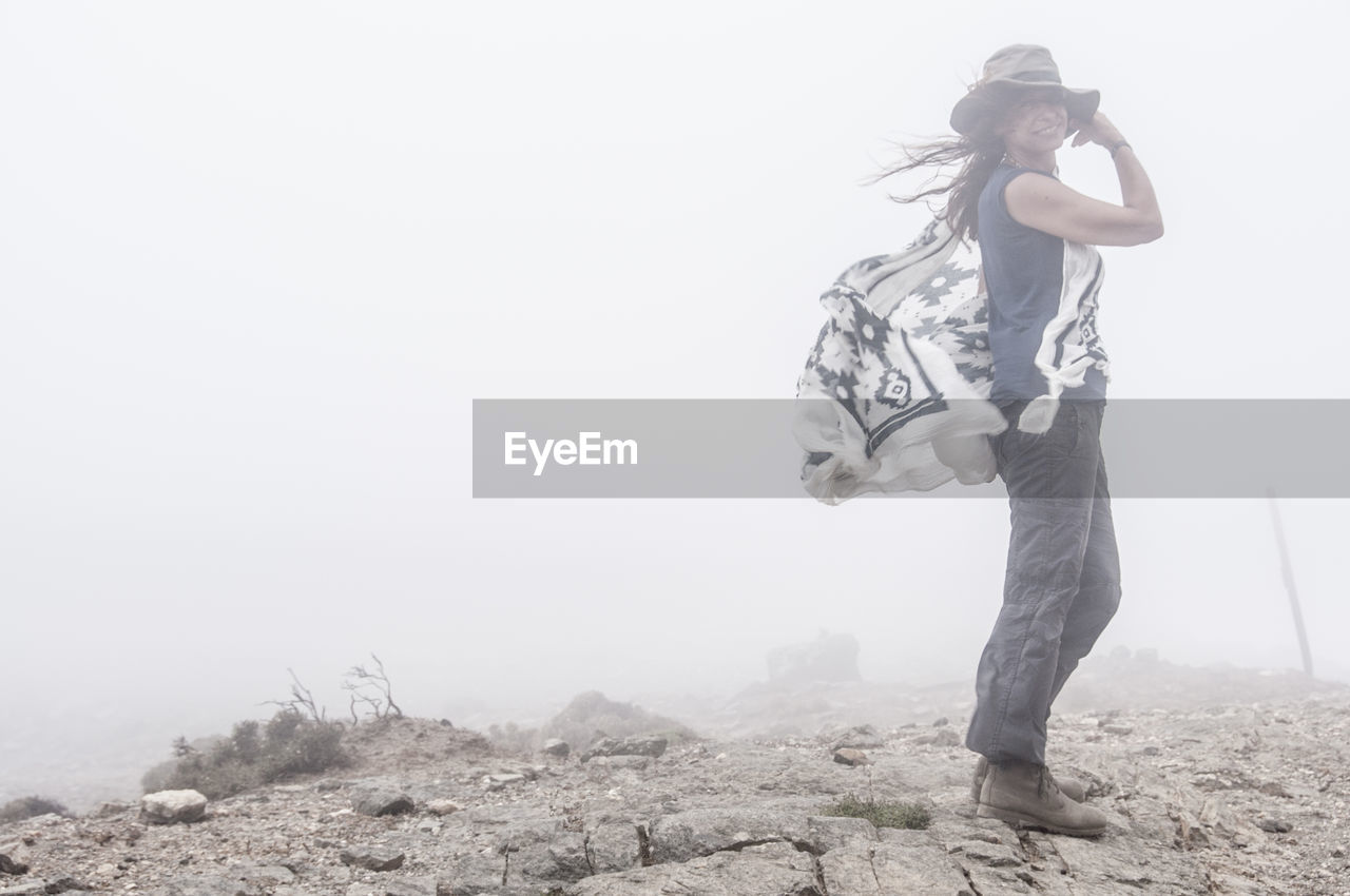 Portrait of woman standing on mountain during foggy weather