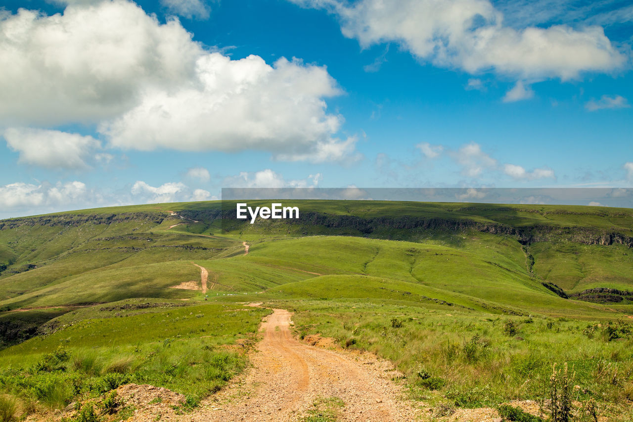 Scenic view of road amidst field against sky