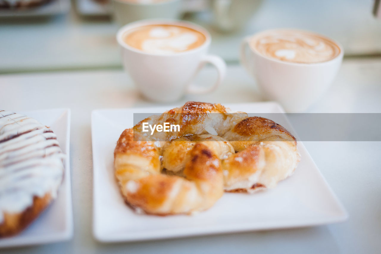 High angle view of croissant with cappuccinos served on table