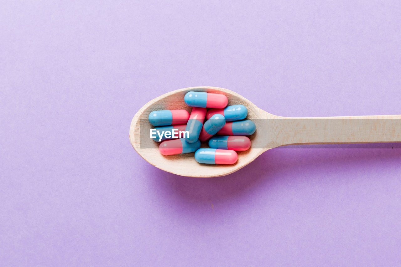 high angle view of pills in spoon on blue background
