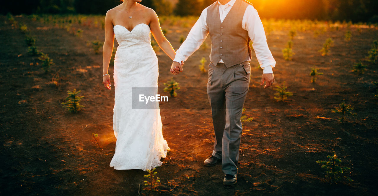 Low section of couple walking on land during sunset