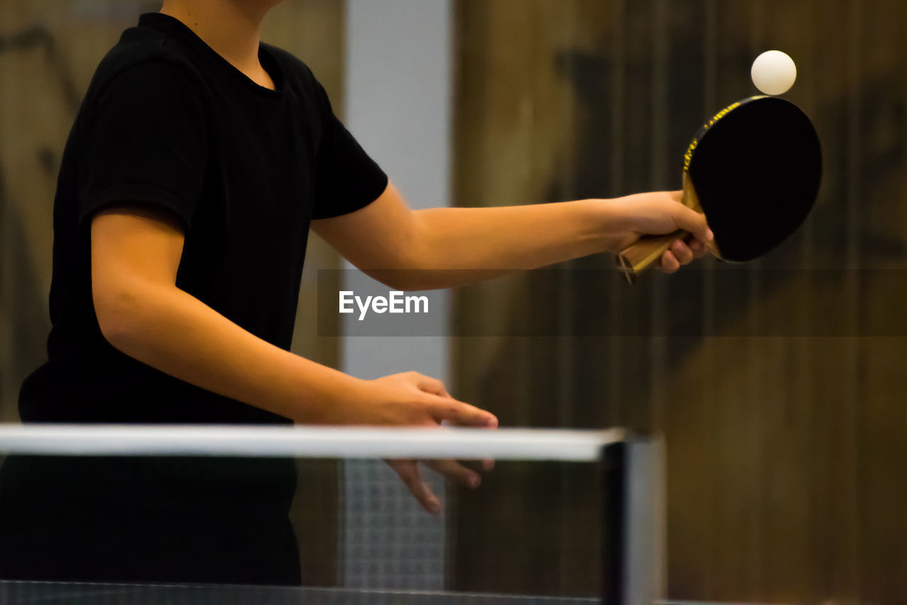 Midsection of man playing table tennis