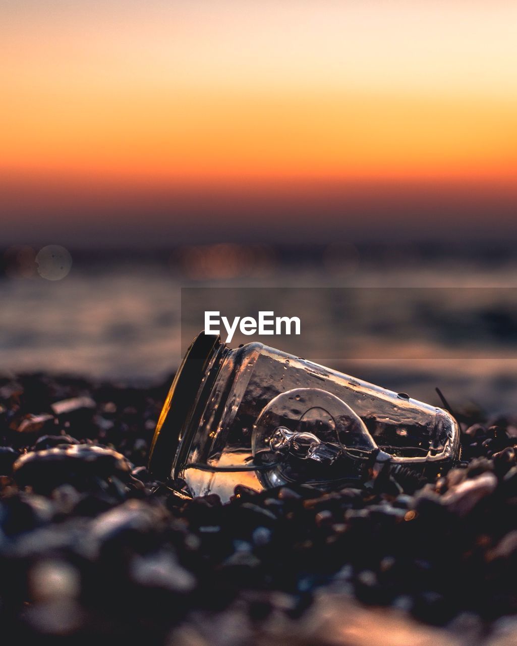 Close-up of light bulb in jar at beach during sunset