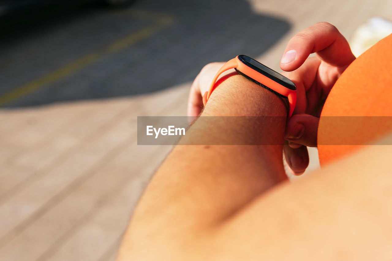 Crop unrecognizable sportswoman with curvy body watching heart rate on wearable tracker during workout on street