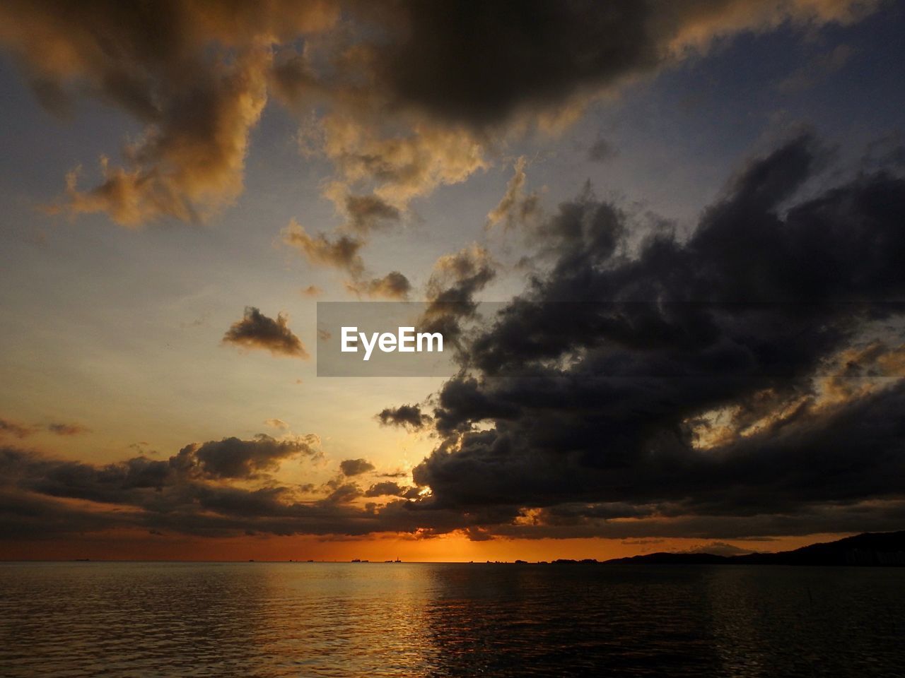 Scenic view of sea against dramatic sky during sunset