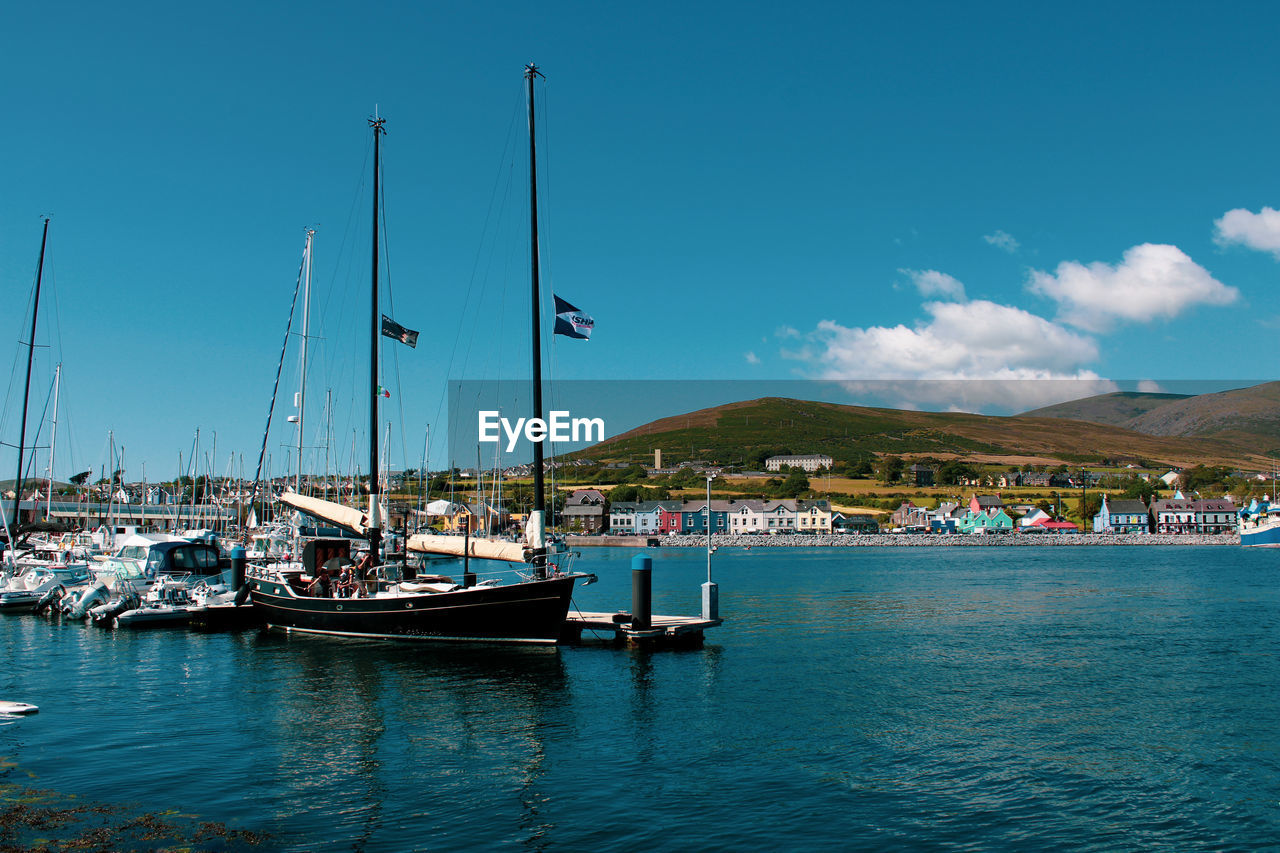 Sailboats moored in sea against blue sky