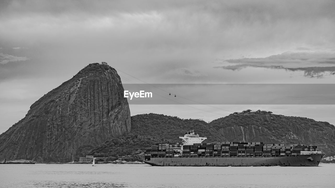 Photo of sugarloaf mountain with a cargo ship passing in front of it in guanabara bay