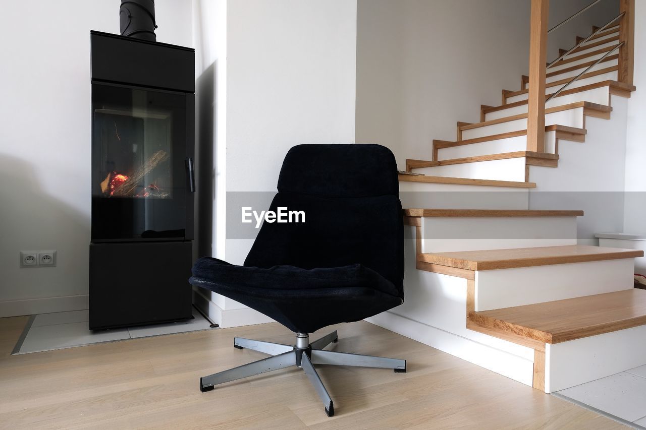 Modern scandinavian living room armchair, staircase and a modern freestanding fireplace.