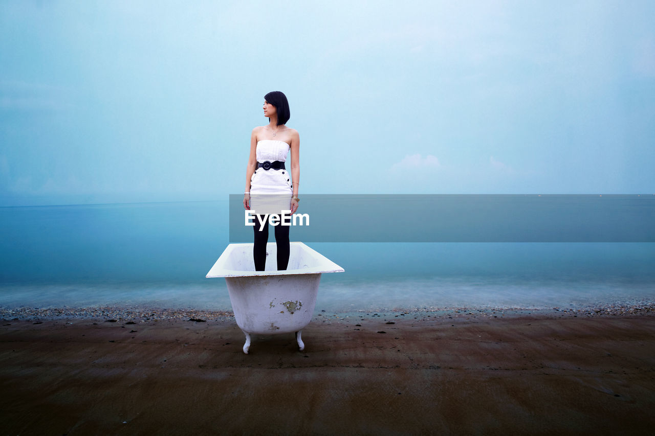 Woman standing in bathtub at beach