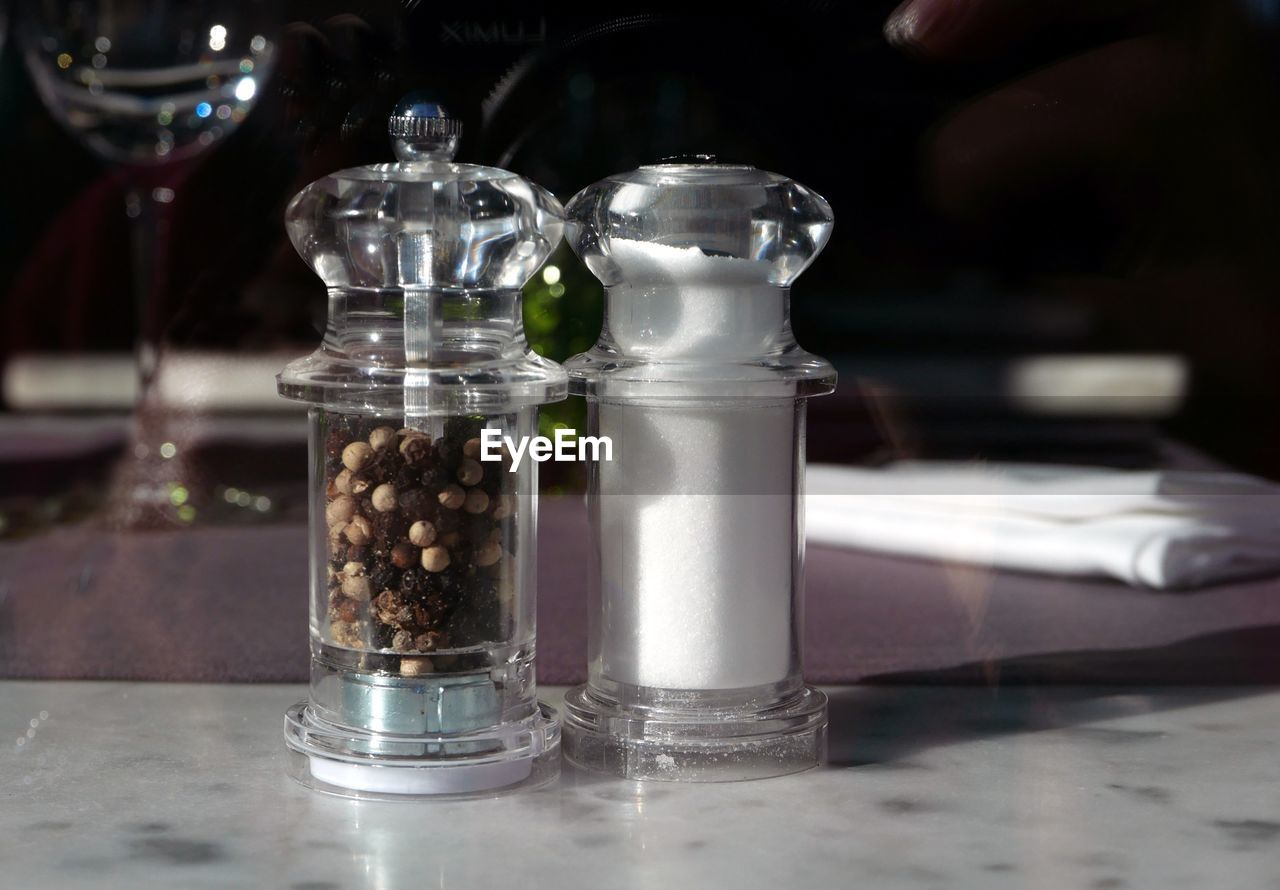 Close-up of salt and peppercorn in glass cellar on table